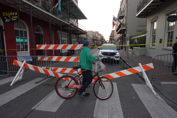 A cyclist passes a police barricade near the scene after a vehicle drove into a crowd on New Orleans' Canal and Bourbon Street, Wednesday Jan. 1, 2025. (AP Photo/Gerald Herbert)