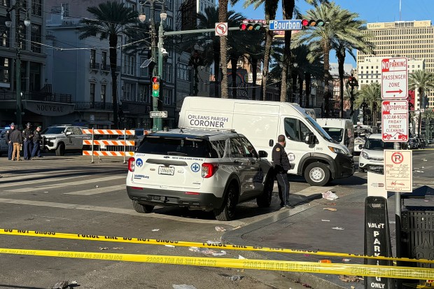 A coroner's van is parked on the corner of Bourbon St. and Canal St, after a vehicle raced into a crowd of revelers early on New Year's Day, in New Orleans on Wednesday, Jan. 1, 2025. (AP Photo/Jack Brook)