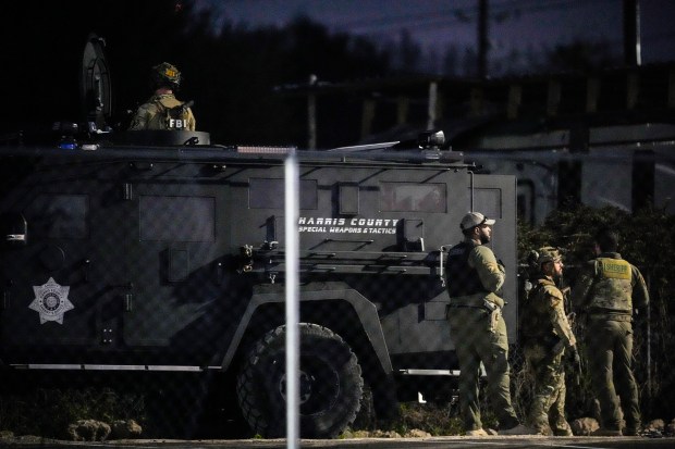 Law enforcement officers stand behind a SWAT vehicle near a location in Houston, Texas, Wednesday, Jan. 1, 2025, where police personnel investigate the place suspected to be associated with an attacker in a deadly rampage in New Orleans. (Brett Coomer/Houston Chronicle via AP)