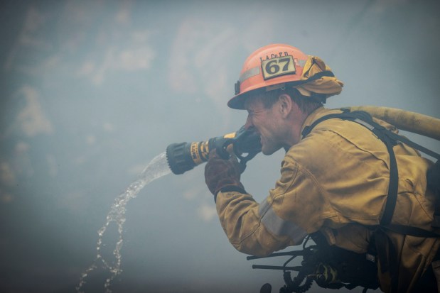 A firefighters make a stand in front of the advancing Palisades Fire in the Pacific Palisades neighborhood of Los Angeles, Tuesday, Jan. 7, 2025. (AP Photo/Ethan Swope)