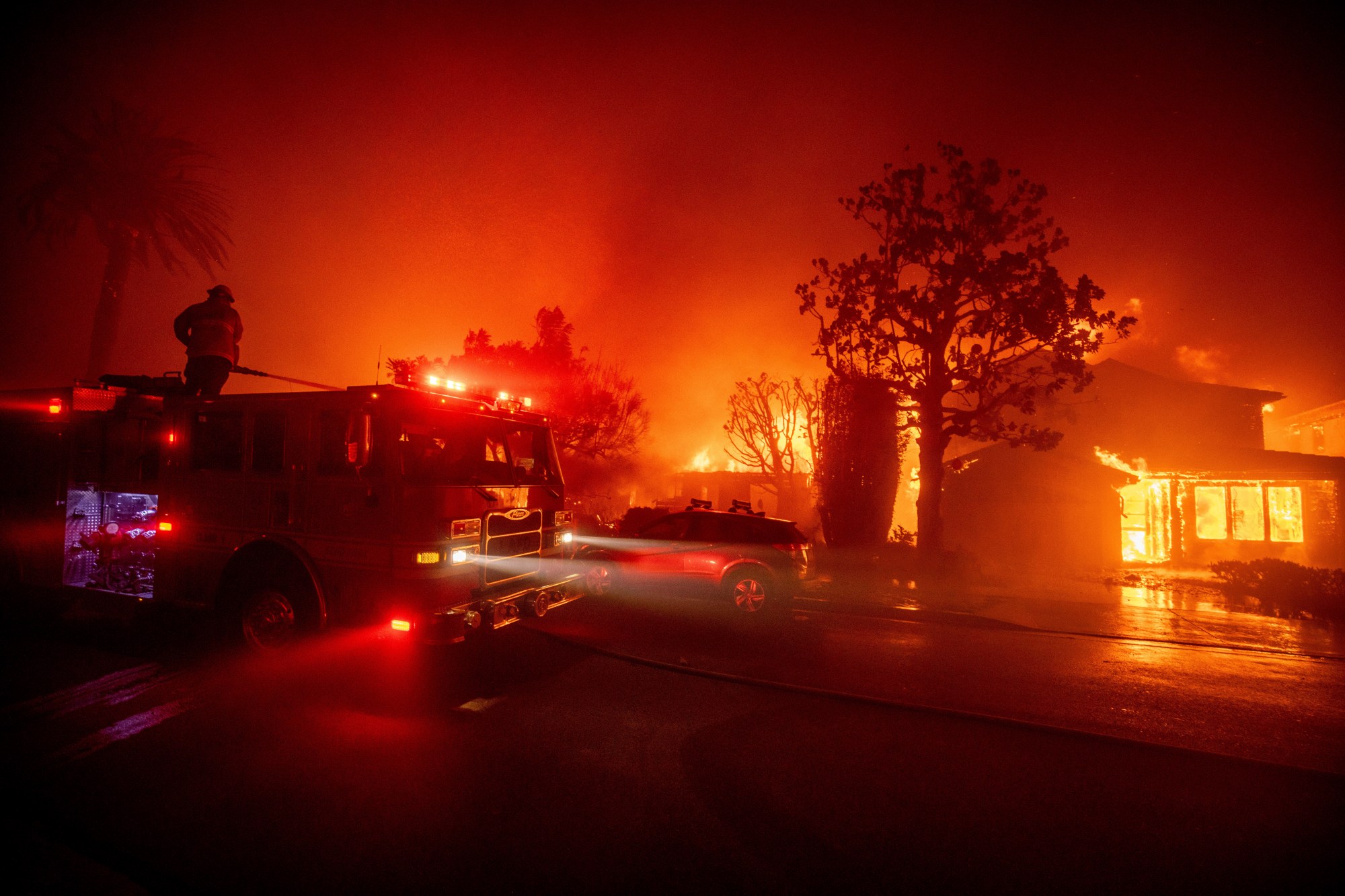 Fire crews battle the Palisades Fire as it burns multiple structures in the Pacific Palisades neighborhood of Los Angeles, Tuesday, Jan. 7, 2025. (AP Photo/Ethan Swope)