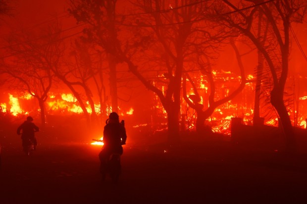 Two people ride by on motorcycles as the Palisades Fire destroys an area in the Pacific Palisades neighborhood