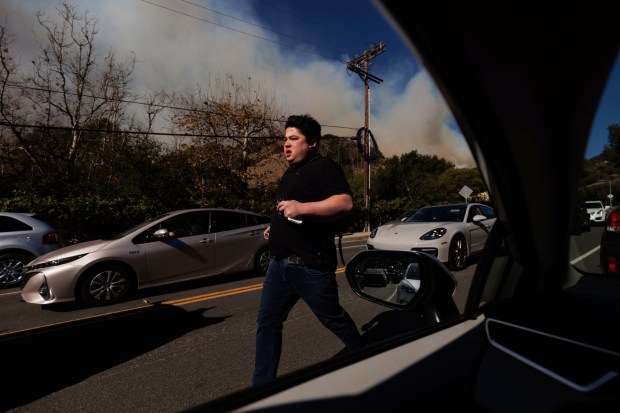 A person flees from an advancing wildfire in the Pacific Palisades neighborhood 