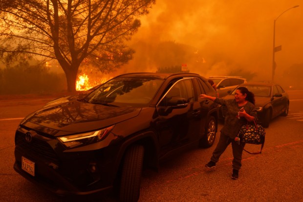 A woman cries as the Palisades Fire advances in the Pacific Palisades neighborhood