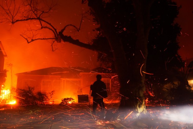 A person tries to hose down embers from the Palisades Fire