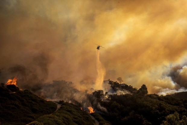 Water is dropped on the advancing Palisades Fire by helicopter 