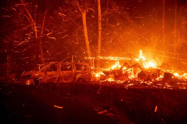 The Eaton Fire burns vehicles and structures Wednesday, Jan. 8, 2025 in Altadena, Calif. (AP Photo/Ethan Swope)