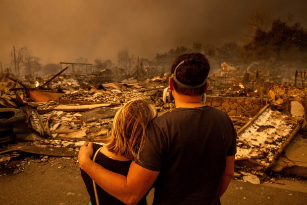 Megan Mantia, left, and her boyfriend Thomas, return to Mantia's fire-damaged home after the Eaton Fire swept through, Wednesday, Jan. 8, 2025 in Altadena, Calif. (AP Photo/Ethan Swope)