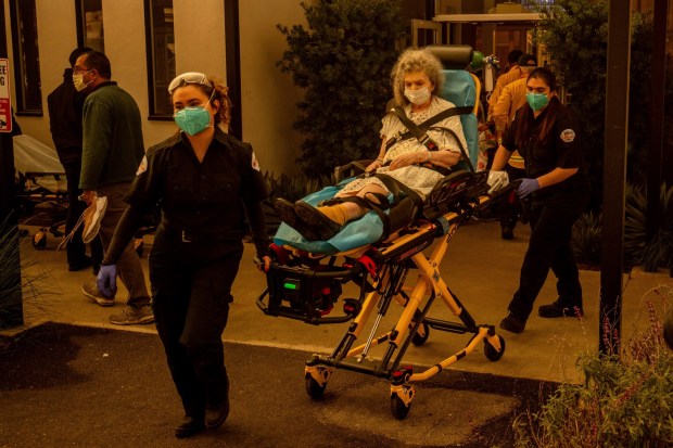 A resident is evacuated from a senior living facility as the Eaton Fire approaches Wednesday, Jan. 8, 2025, in Altadena, Calif. (AP Photo/Ethan Swope)