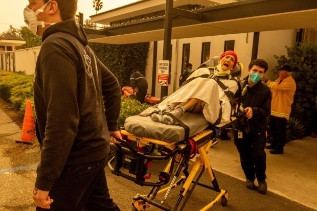 A resident is evacuated from a senior living facility as the Eaton Fire approaches Wednesday, Jan. 8, 2025, in Altadena, Calif. (AP Photo/Ethan Swope)