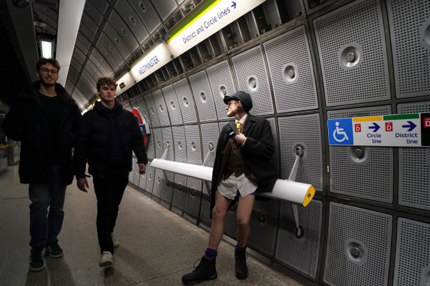 A man sits by the platform of an underground station, during the annual event "No Trousers Tube Ride" in London, Sunday, Jan. 12, 2025. (AP Photo/Alberto Pezzali)