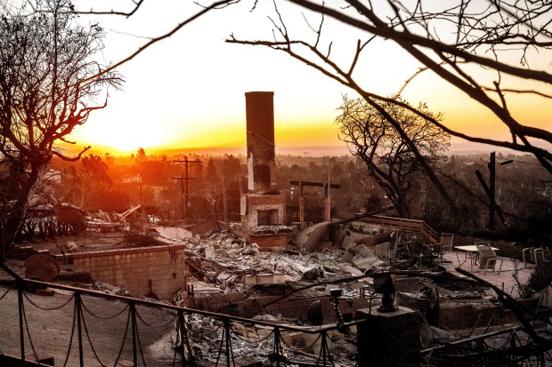 The sun rises behind a home destroyed by the Palisades Fire in the Pacific Palisades community of Los Angeles on Sunday, Jan. 12, 2025.