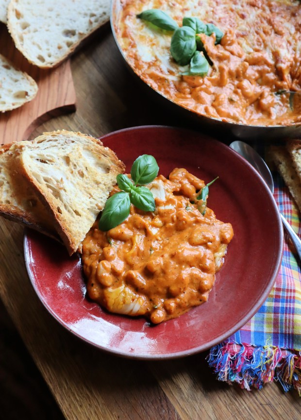 A slice of bread on a plate with a serving of cheesy beans