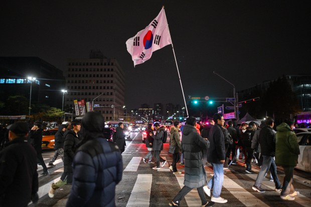 A man holds the South Korea flag outside the National Assembly in Seoul on December 4, 2024, after President Yoon Suk Yeol declared emergency martial law.