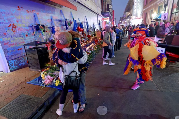 NEW ORLEANS, LOUISIANA - JANUARY 4: People embrace in front of a memorial on Bourbon Street at Canal Street as Jennifer Jones (R) dances on January 4, 2025 in New Orleans, Louisiana. Fourteen people were killed and over 30 were injured when a driver intentionally drove into a crowd on Bourbon Street in the early morning hours of New Year's Day in what police are calling a terrorist attack. (Photo by Michael DeMocker/Getty Images)